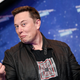 Elon Musk is shown making a funny face and giving two thumbs up.